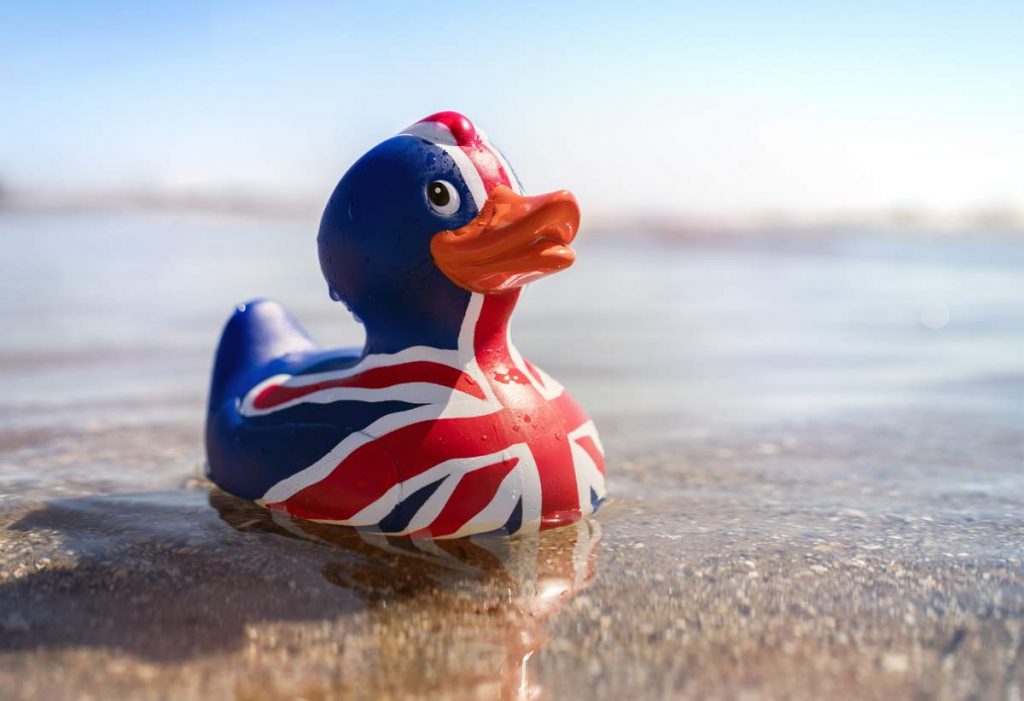 British flag rubber duck in the sea at the beach