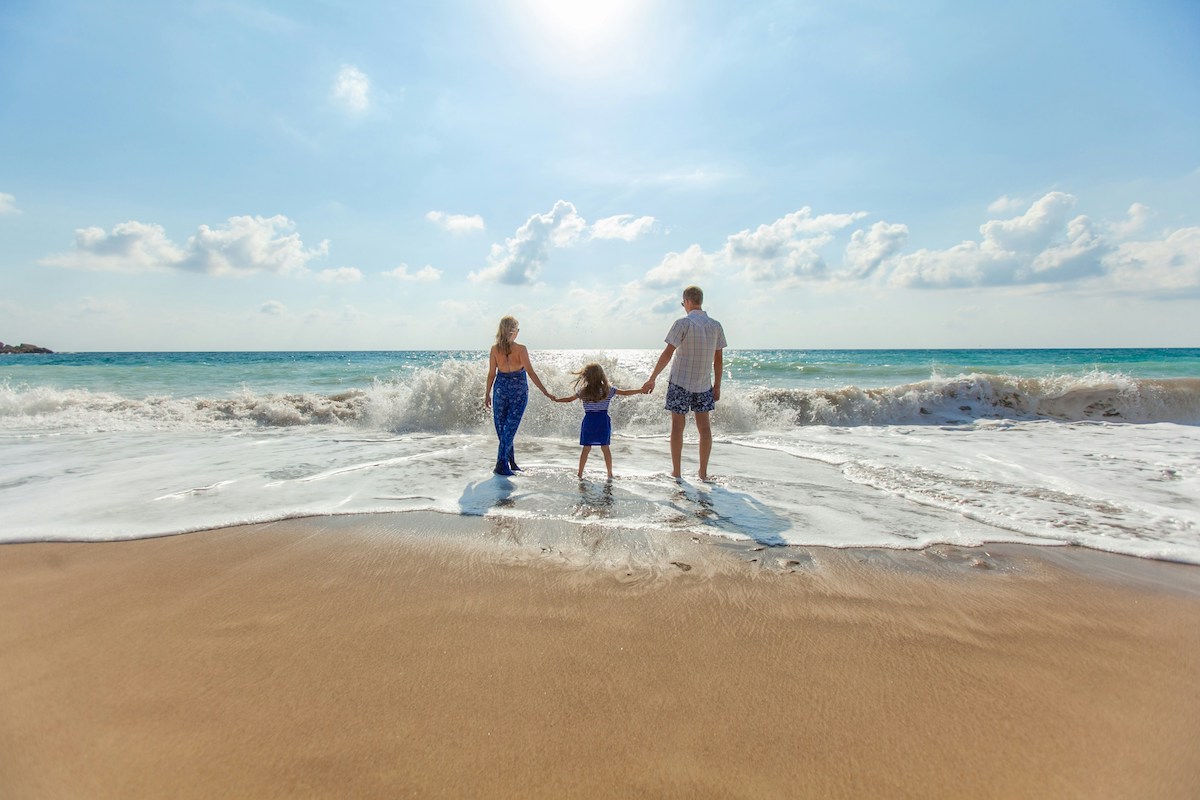 Family on a golden sand beach standing in the shoreline