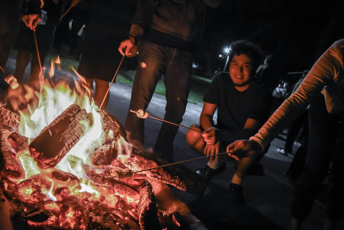 A group of people melting marshmallows on a fire