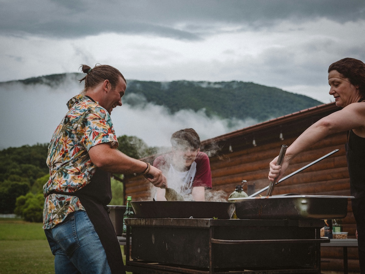 Three people cooking on a bbq on a working holiday