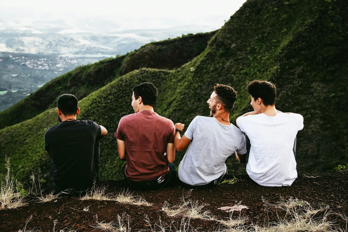 Four men sat on a hill top laughing 