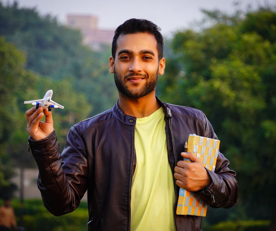 A man holding a small toy plane with a green jungle background